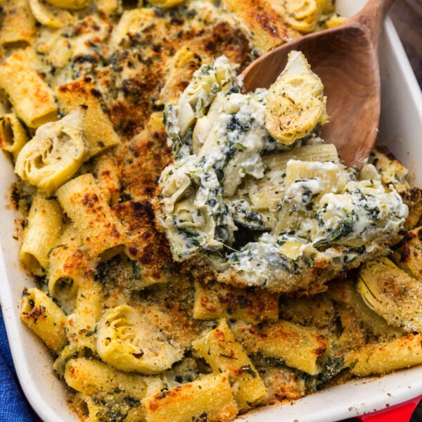 Large spoon scooping baked artichoke pasta.
