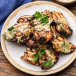 Plate of grilled chicken thighs with Italian dressing and parsley garnish.