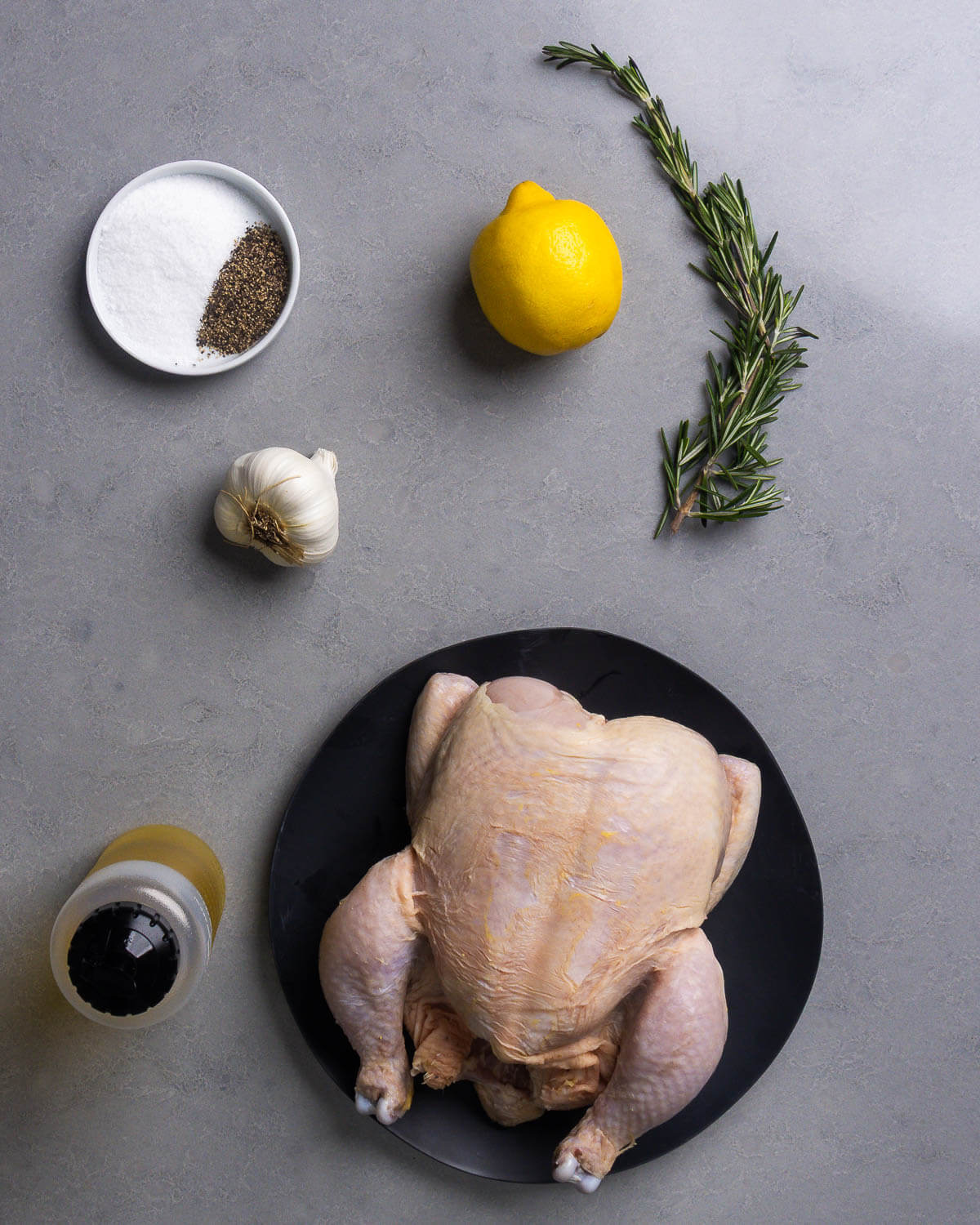 Ingredients shown: salt, pepper, lemon, rosemary, garlic, olive oil, and whole chicken.