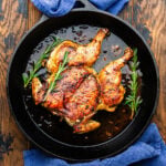 Roasted Tuscan chicken under a brick in cast iron pan.