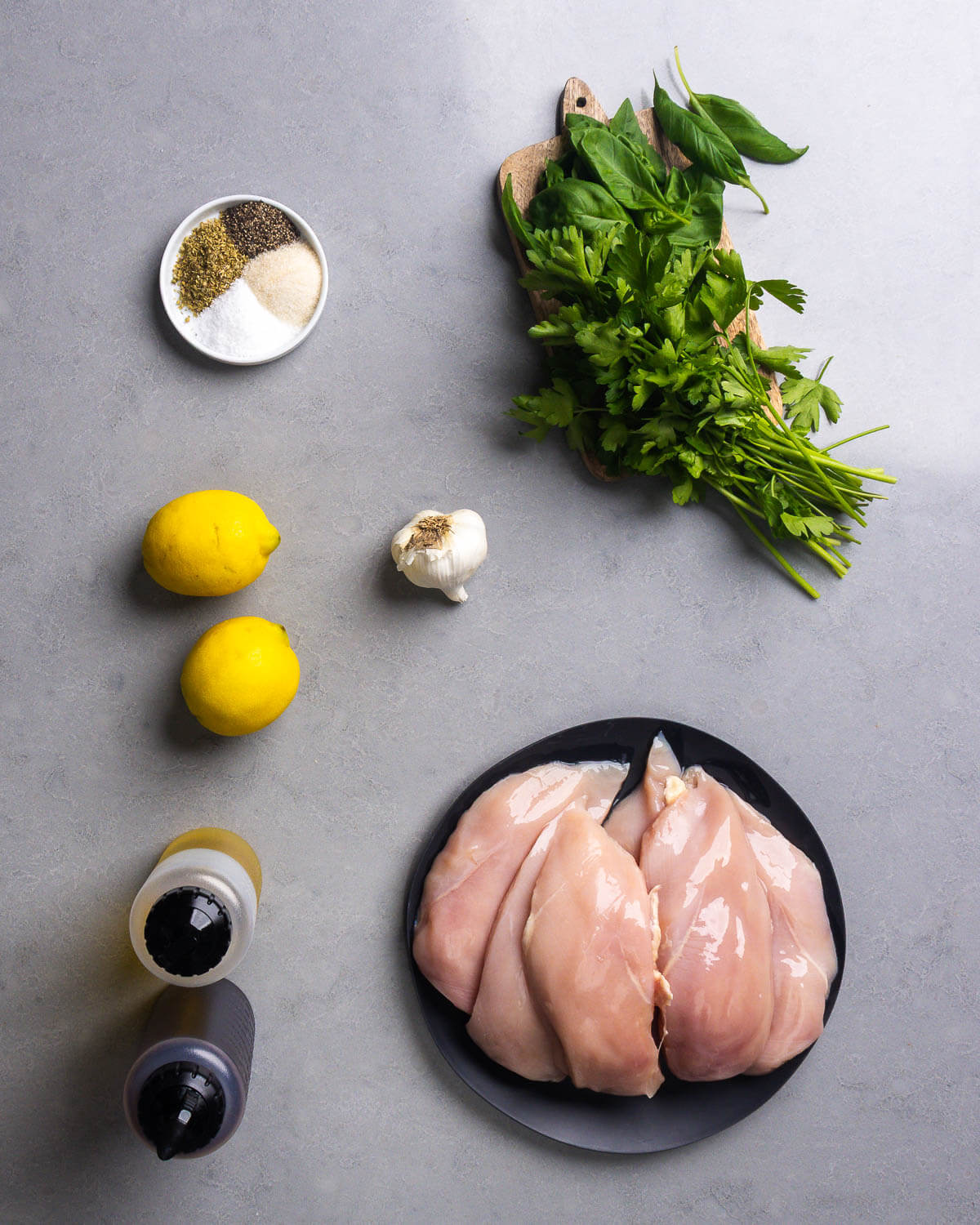Ingredients shown: spices, basil, parsley, lemons, garlic, olive oil, red wine vinegar, and chicken breasts.