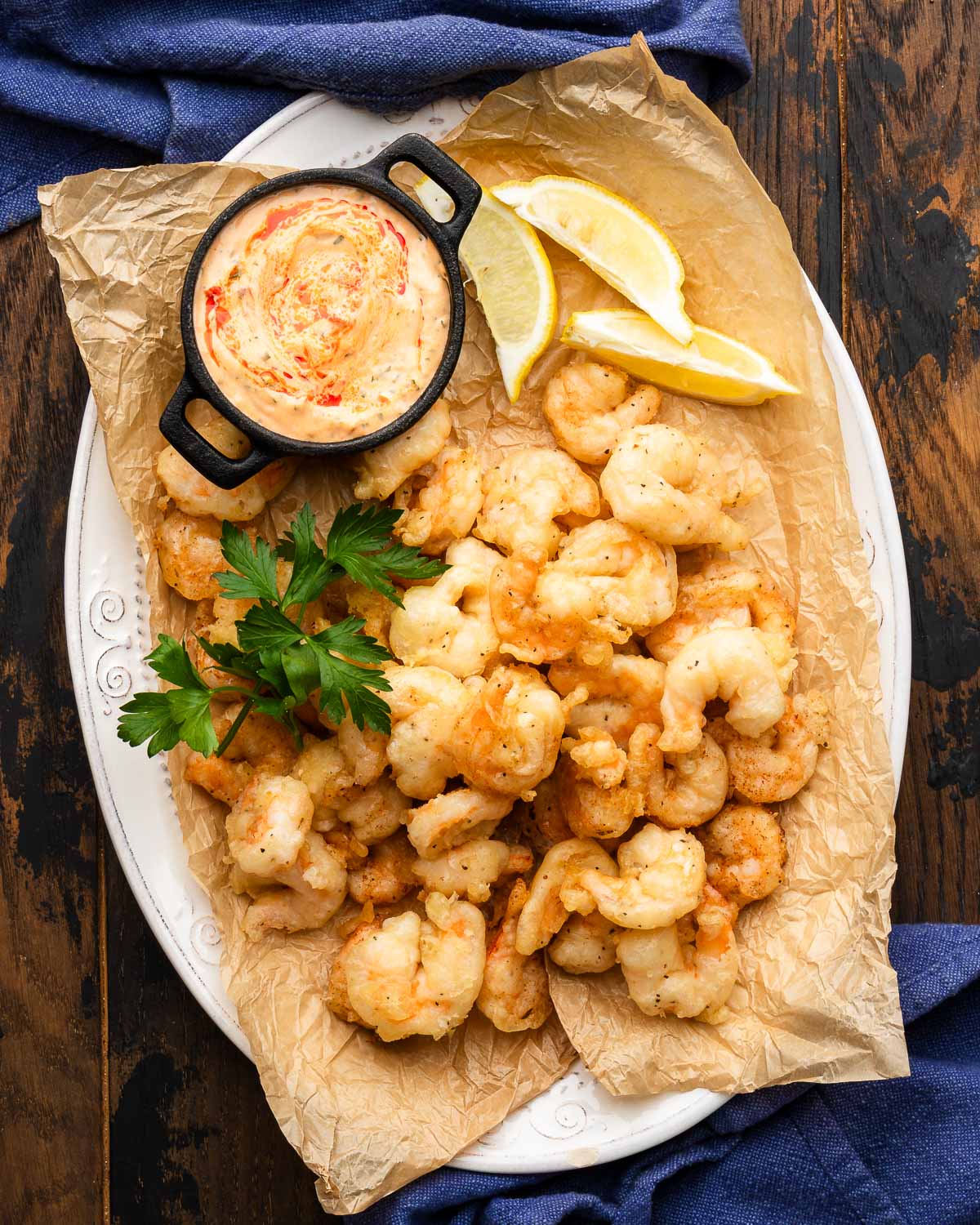Large platter of fried shrimp with lemon wedges and dipping sauce.