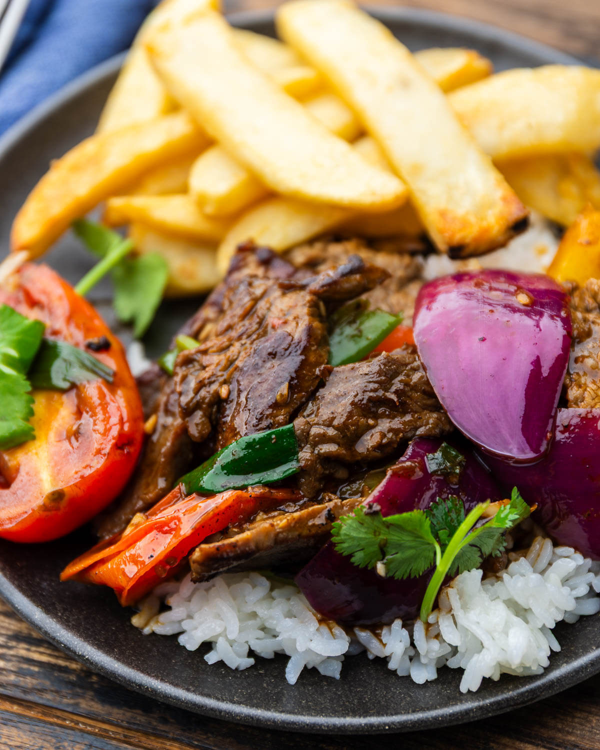 Lomo saltado over white rice with french fries.