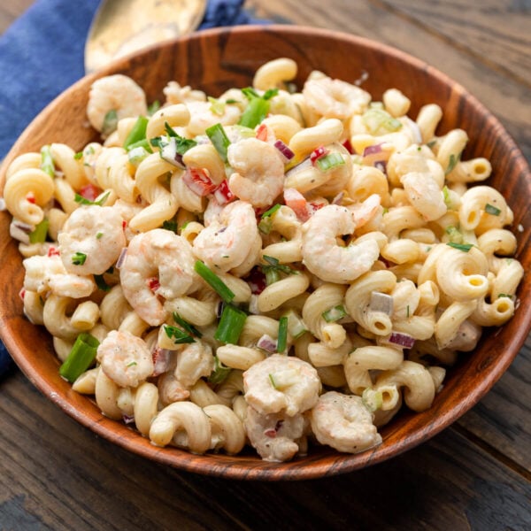 Wood bowl with shrimp macaroni salad topped with green onion.