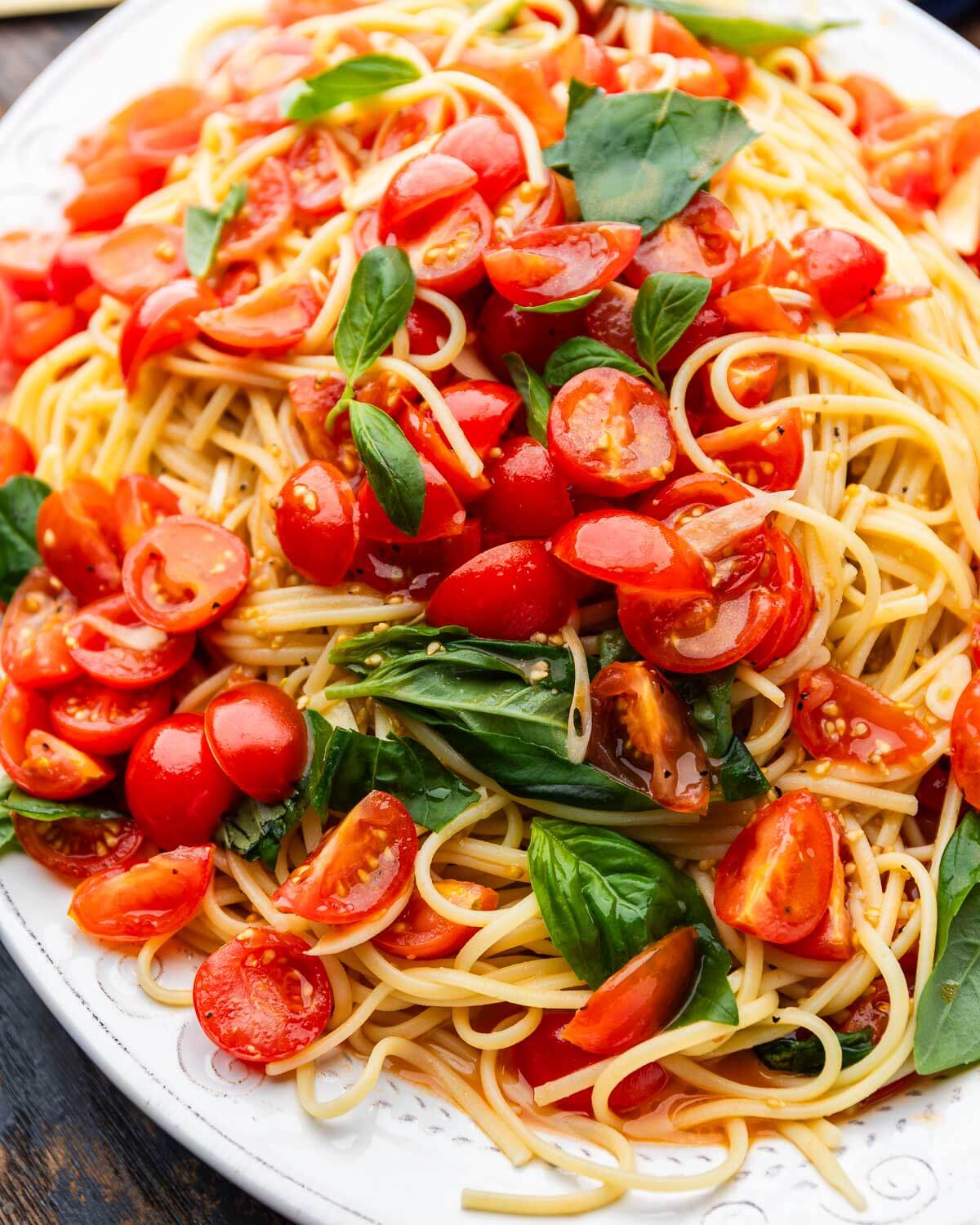 Large platter with linguine topped with an uncooked tomato sauce.