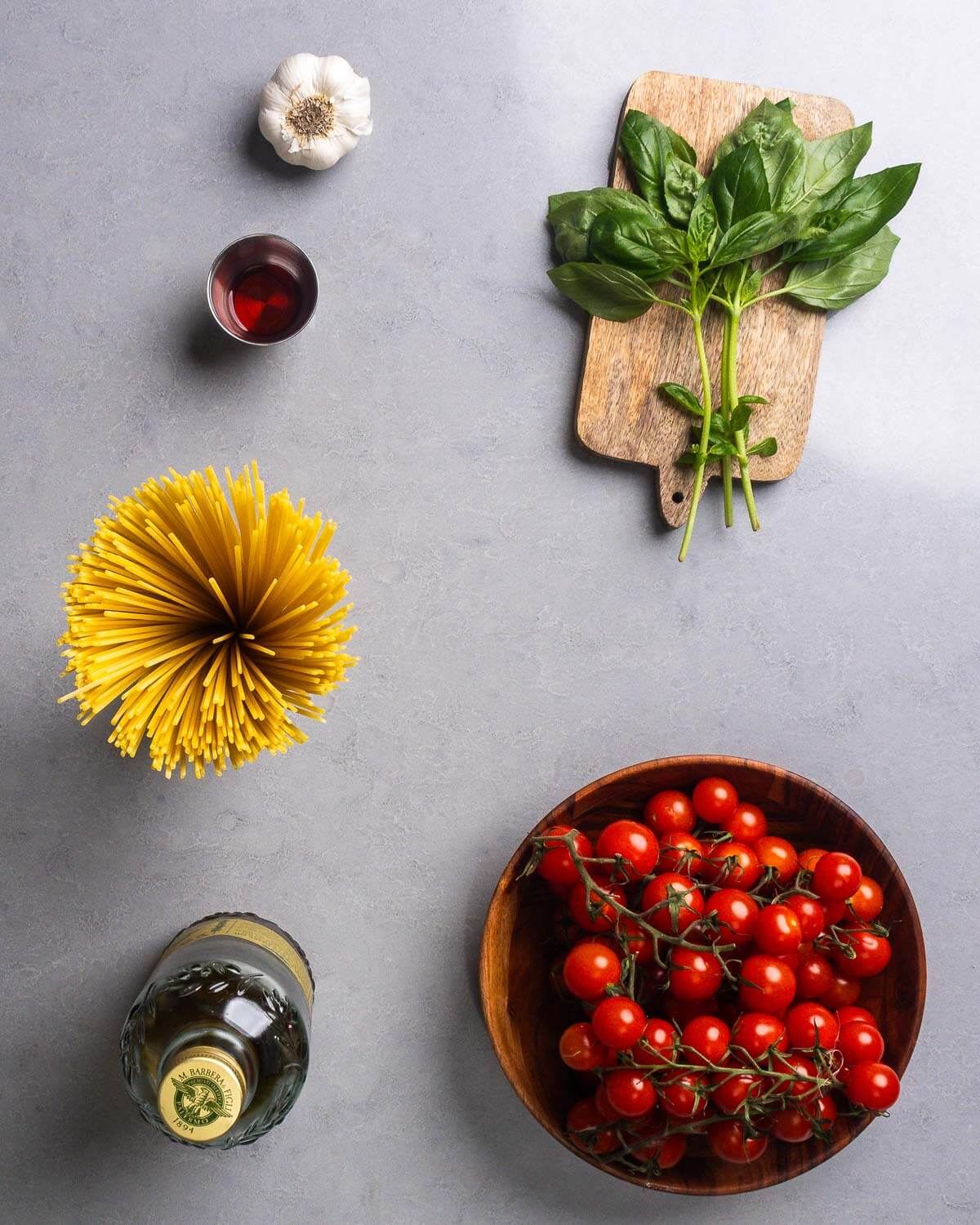 Ingredients shown: garlic, red wine vinegar, basil, pasta, olive oil, and cherry tomatoes.