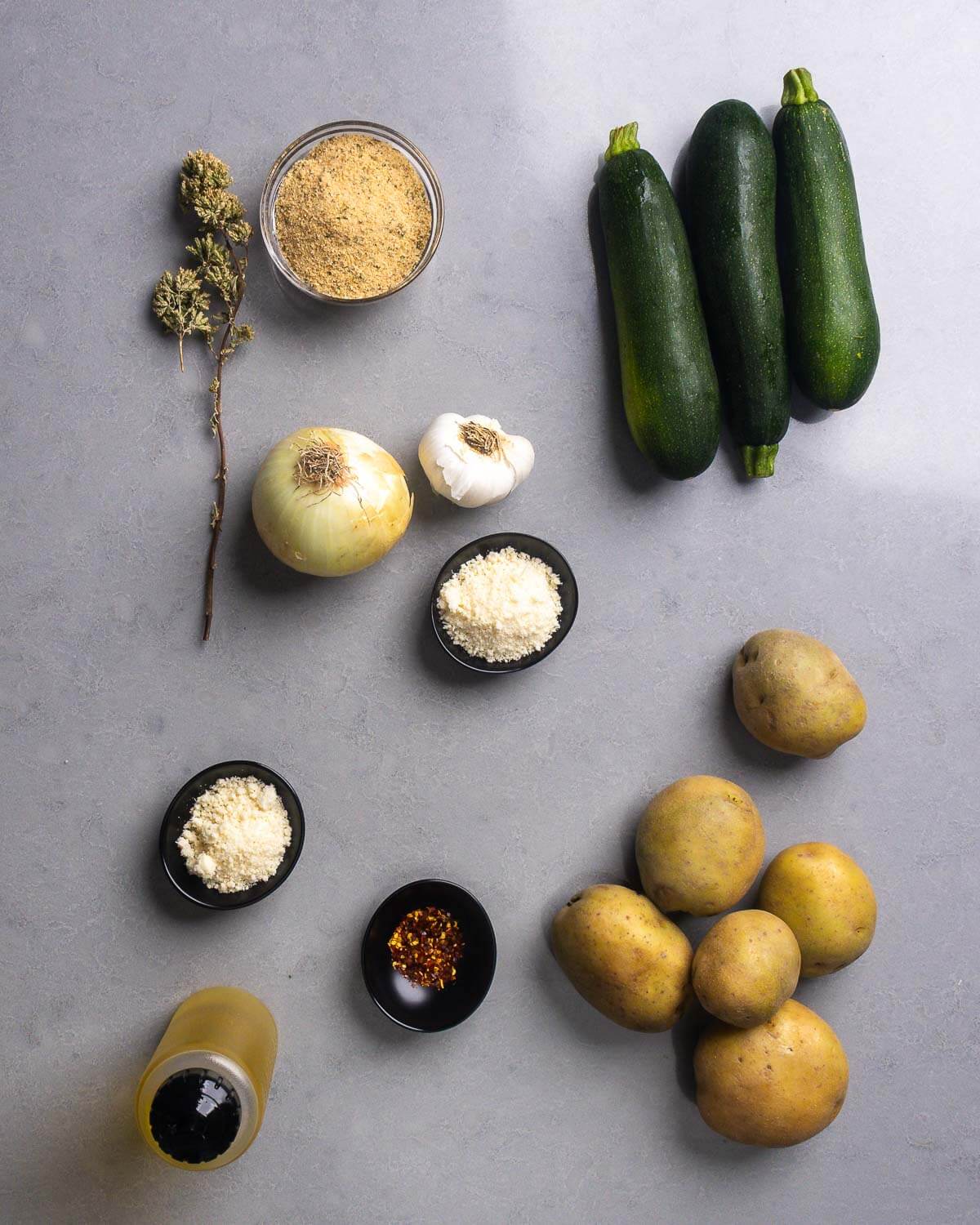 Ingredients shown: sicilian oregano, breadcrumbs, onion, garlic, pecorino romano, zucchini, olve oil, hot red pepper flakes, and potatoes.