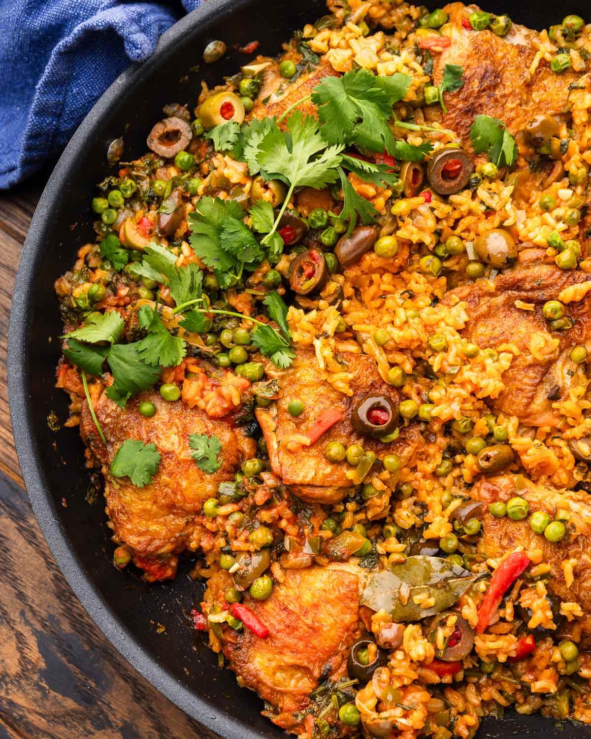 Black pan with arroz con pollo topped with cilantro garnish.