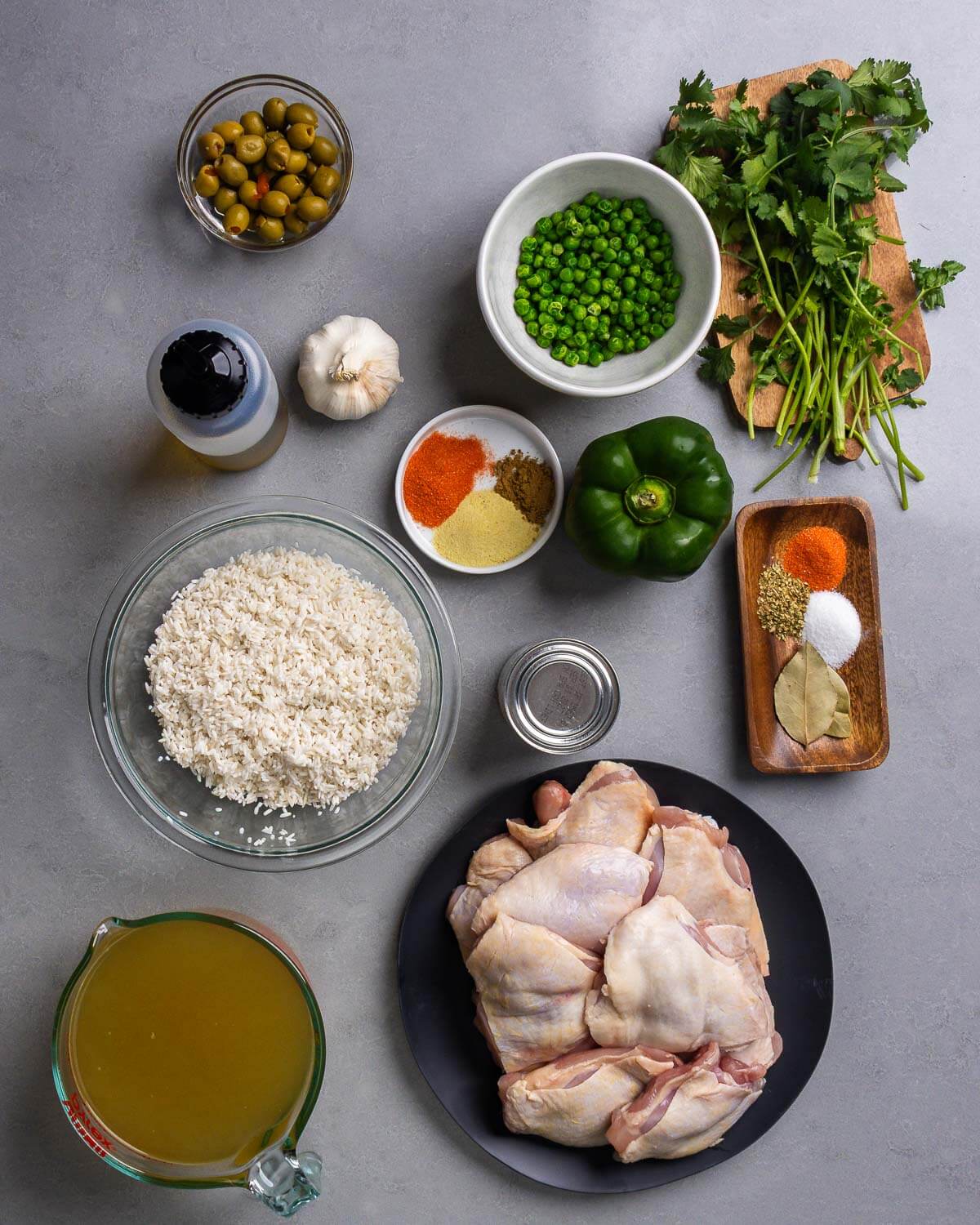 Ingredients shown: olives, peas, cilantro, olive oil, garlic, spices, bell pepper, rice, tomato sauce, chicken stock, and chicken thighs.