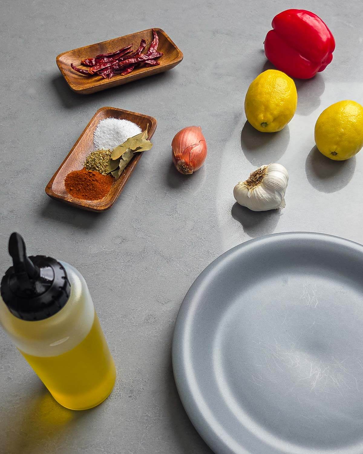 Ingredients shown: birds eye chilis, bell pepper, lemons, shallot, garlic, salt, smoked paprika, oregano, bay leaves, and olive oil.