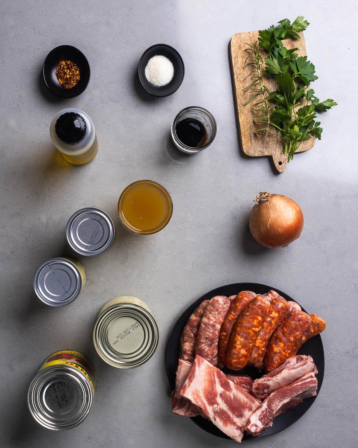 Ingredients shown: hot red pepper flakes, olive oil, sugar, balsamic vinegar, rosemary, parsley, canned beans, chicken stock, onion, canned tomatoes, Italian sausage, and baby back ribs.