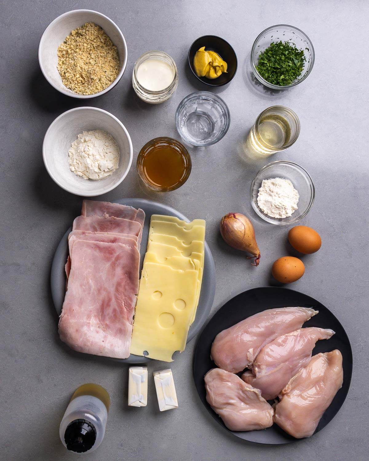 Ingredients shown: breadcrumbs, heavy cream, Dijon mustard, parsley, water, flour, chicken stock, wine, ham, swiss cheese, shallot, eggs, neutral oil, butter, and chicken breasts.