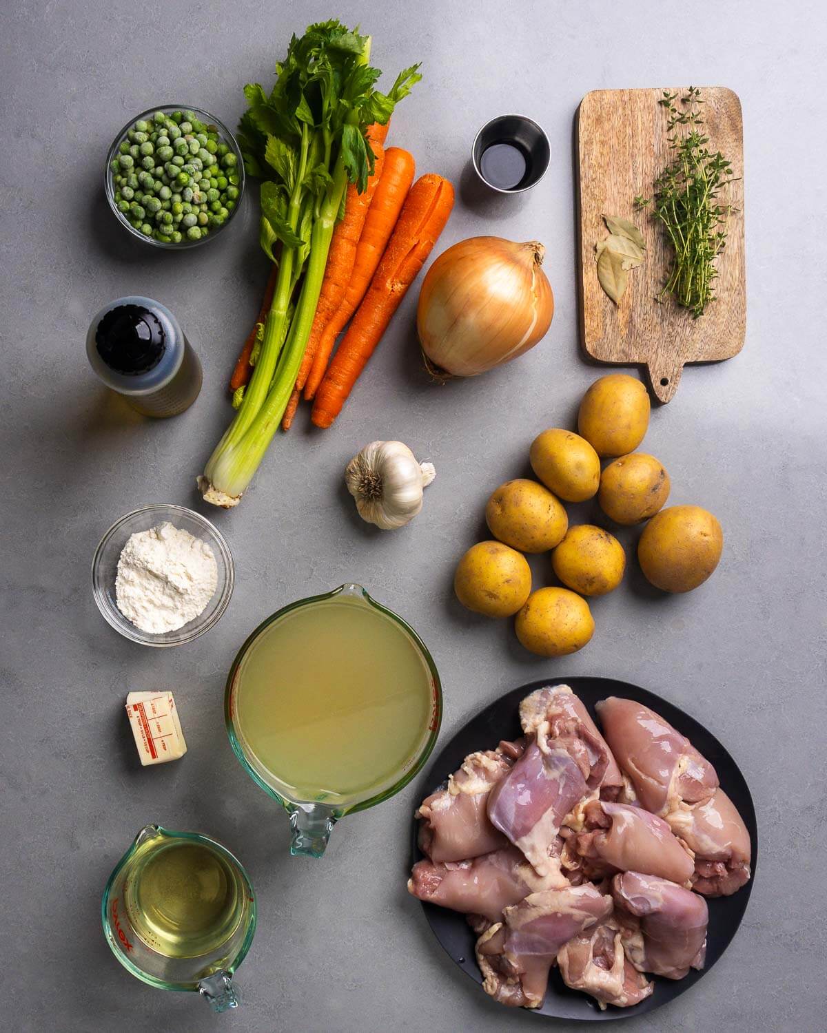 Ingredients shown: olive oil, peas, celery, carrots, worcestershire sauce, onion, bay leaves, thyme, flour, garlic, potatoes, butter, chicken stock, wine, and chicken thighs.