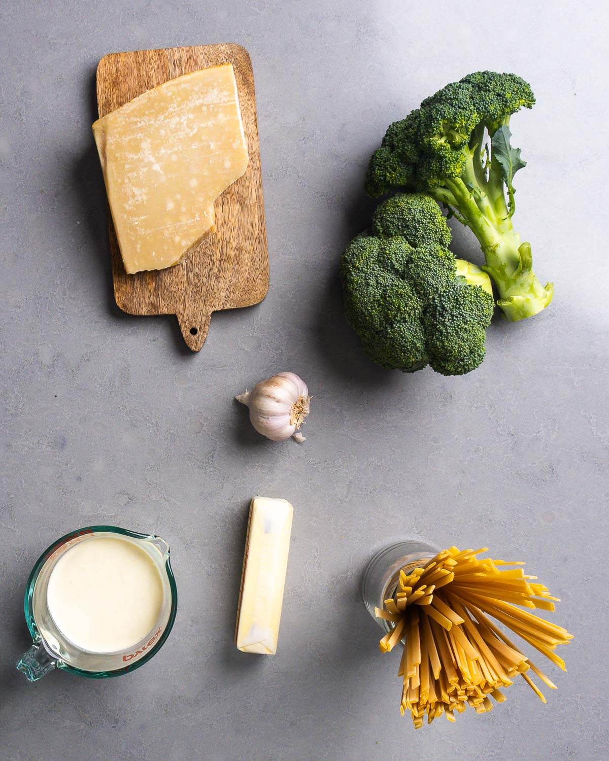 Ingedients shown: block of Parmigiano Reggiano, broccoli, garlic, heavy cream, butter, and fettuccine.