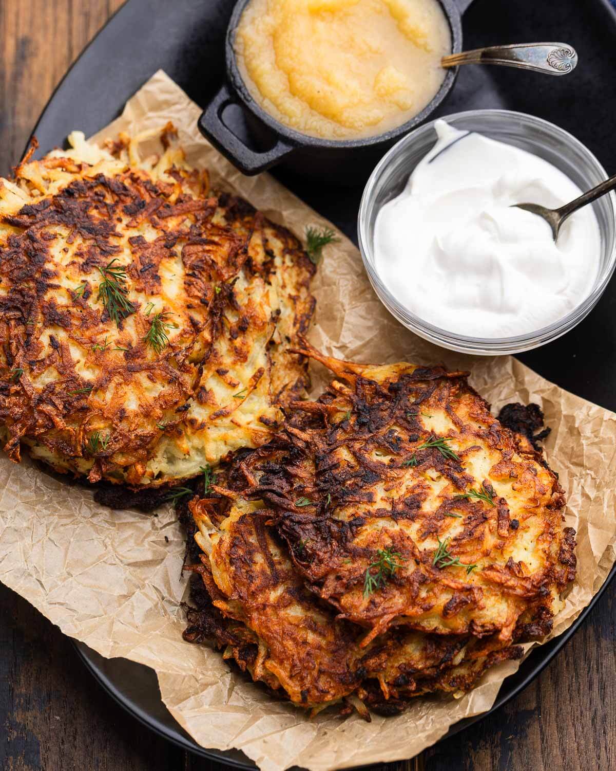 Small platter with German potato pancakes with applesauce and sour cream on the side.