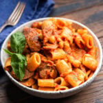 Large bowl with sausage chickpea pasta garnished with basil.