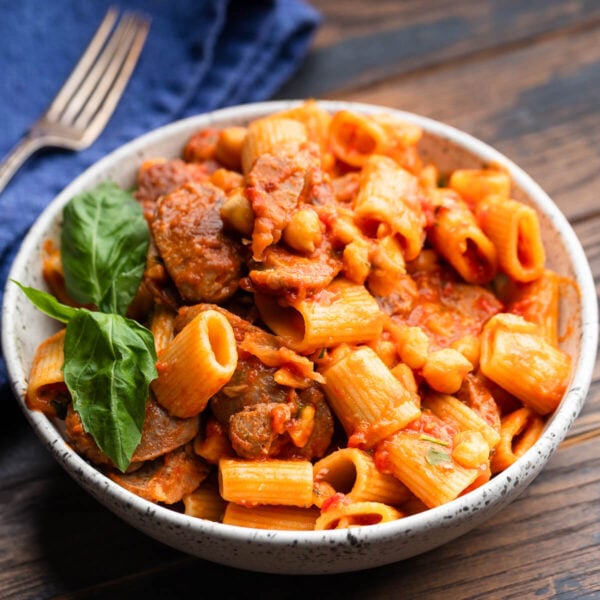 Large bowl with sausage chickpea pasta garnished with basil.