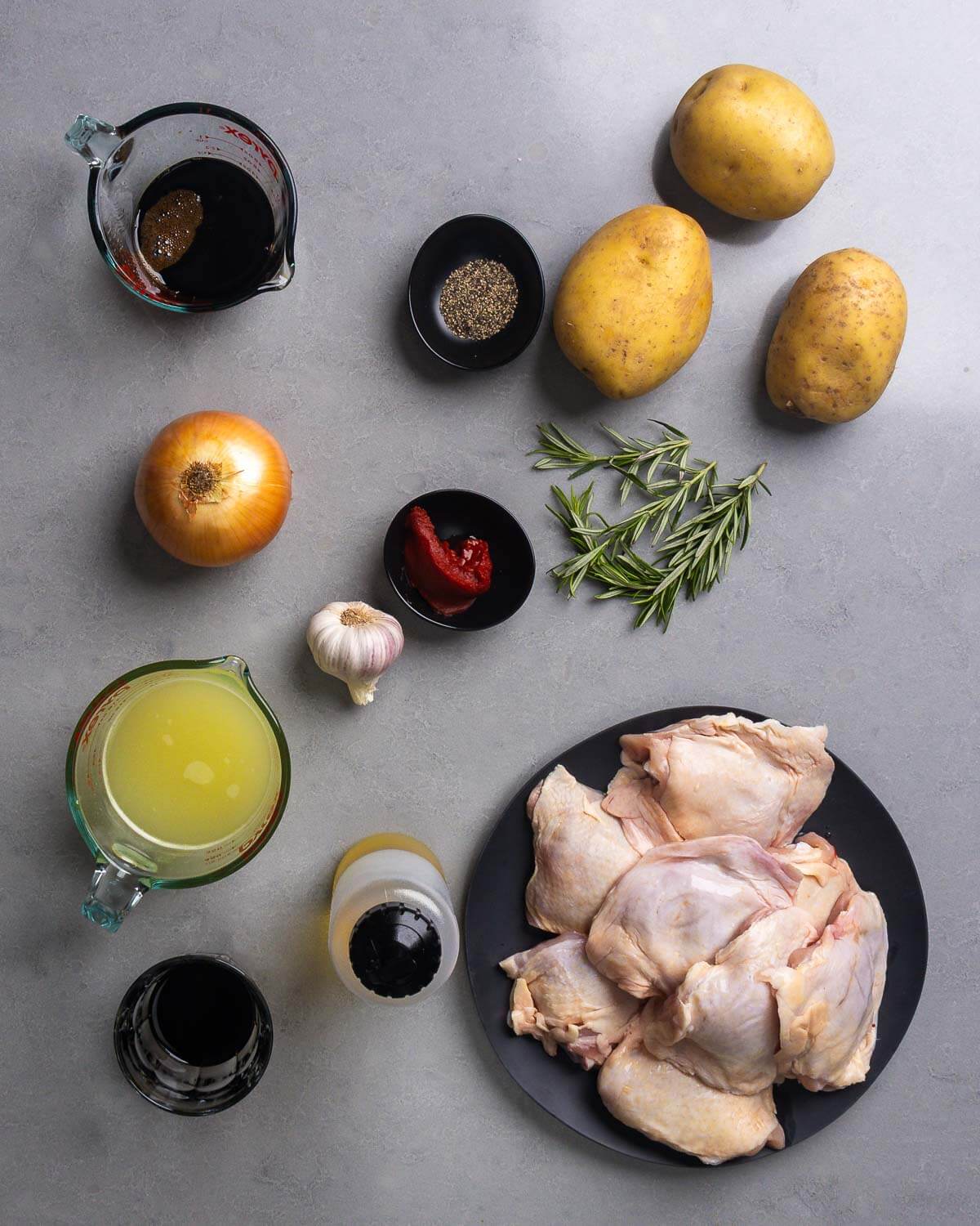 Ingredients shown: balsamic vinegar, black pepper, potatoes, rosemary, onion, tomato paste, garlic, chicken stock, soy sauce, olive oil, and chicken thighs.