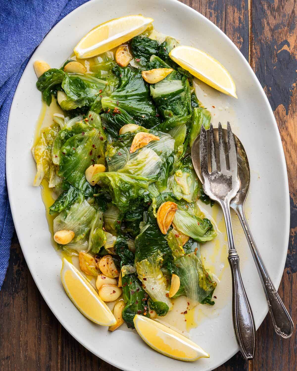 Sauteed escarole with garlic and oil in white platter.