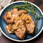 Blue plate with 2 slices of meatloaf topped with brown mushroom gravy.
