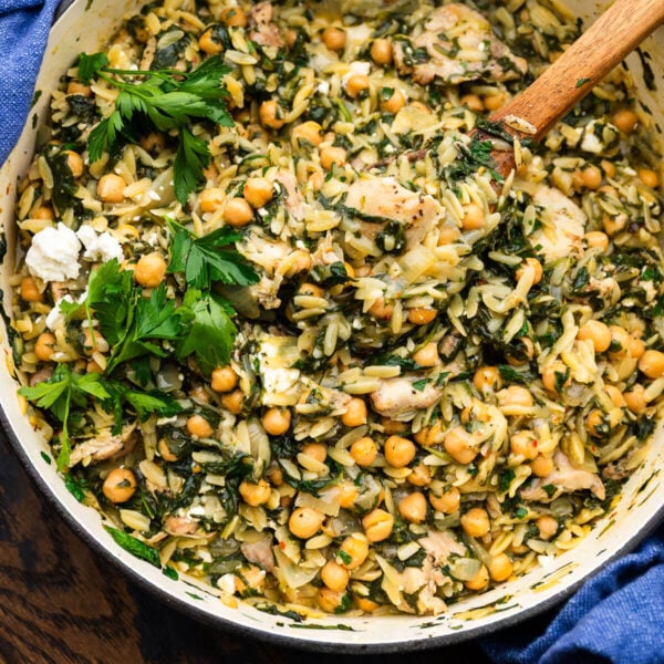 Large pot with spinach chicken orzo topped with fresh parsley.