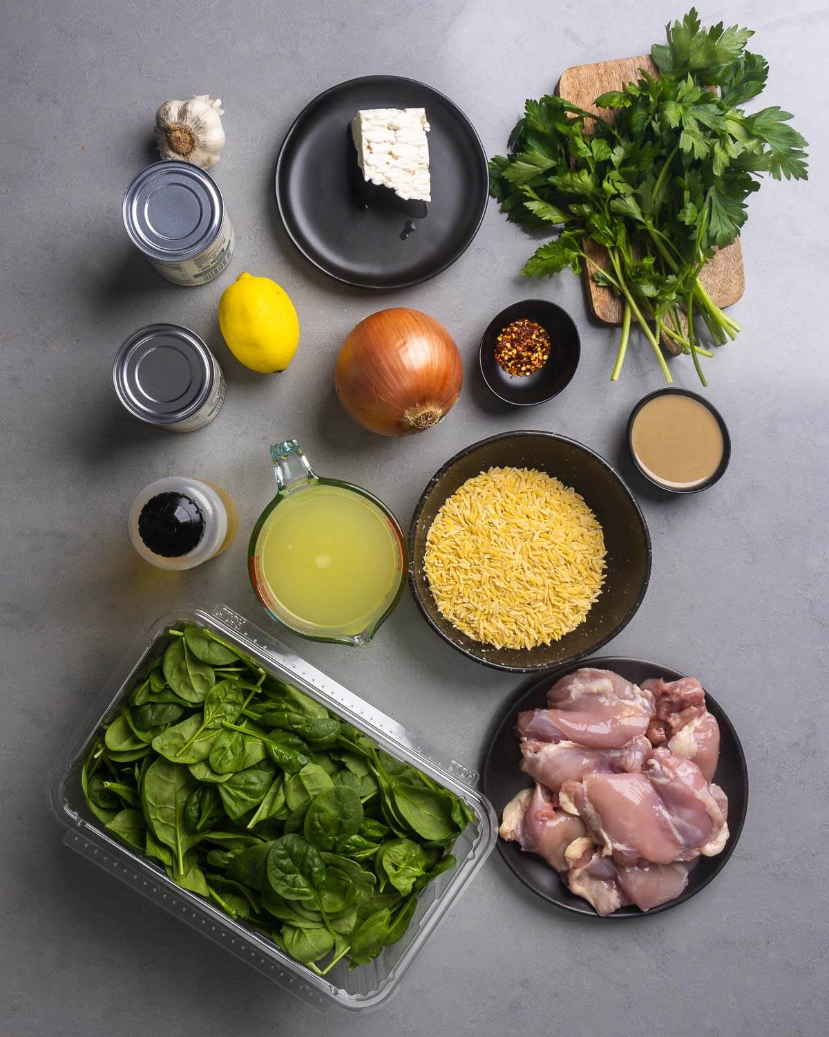 Ingredients shown: garlic, chickpeas, lemon, feta, onion, hot red pepper flakes, parsley, olive oil, chicken stock, orzo, tahini, baby spinach, and chicken thighs.